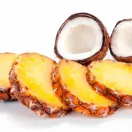 Tajadas de piña y un coco partido por la mitad, dos frutas tropicales.