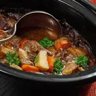 Estofado de carne y verduras siendo preparado en una olla de cocción lenta.