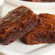 Dos brownies sobre un plato blanco, una de las recetas con chocolate más famosas. 