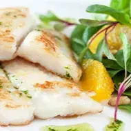 Pescado a la plancha con una ensalada fresca y pequeños brotes.
