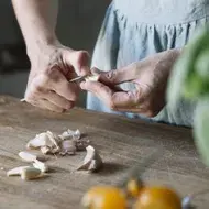 Mujer pelando ajos con cuchillo, qué hacer al cortarse en la cocina