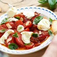 Ensalada caprese con tomate, queso, albahaca y pan en un plato