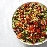Una ensalada cremosa con maíz, tomate y palta en toma cenital.