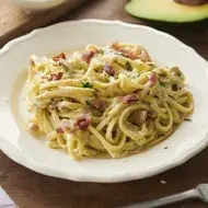 Pasta carbonara con pollo, tocino y hierbas en un plato hondo