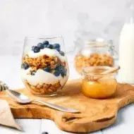 Granola con yogurt griego y miel para alimentarse saludablemente.