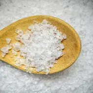 Cuchara de madera con sal marina gruesa, un alimento de origen mineral, sobre una superficie