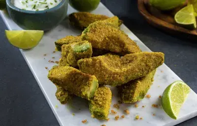 Gajos de palta empanizados y dorados con dip de yogurt, rodajas de limón, servidos como picoteo crujiente
