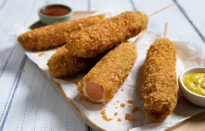 Corn dog coreano crujiente relleno de queso, palitos con kétchup y mostaza