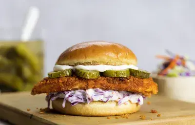 Sándwich de pollo crispy en pan de patata con coleslaw cremoso y pepinillos