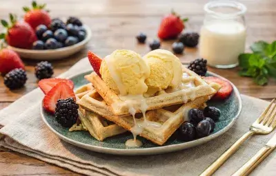 Waffles tibios apilados con dos bolas de helado de vainilla, leche condensada y frutas frescas