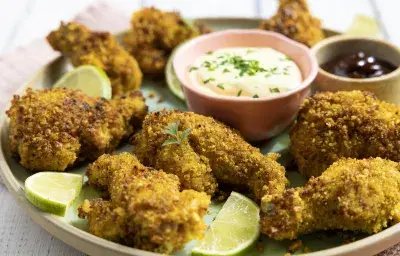 Alitas empanizadas crujientes con sazonador Pimienta Limón MAGGI y gajos de limón, acompañadas de salsas