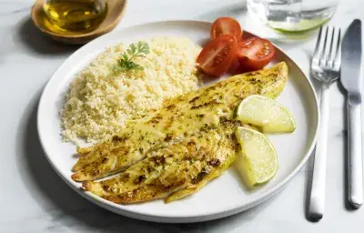 Filetes de pescado blanco a la plancha con hierbas, rodajas de limón y cuscús, servido con tomates cherry