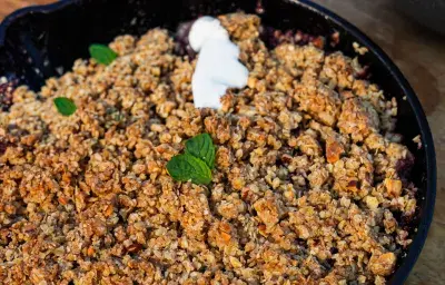 Sarten de fierro con manzana y berries cubiertos de una miga crocante y hojas de menta. Hecho a la parrilla
