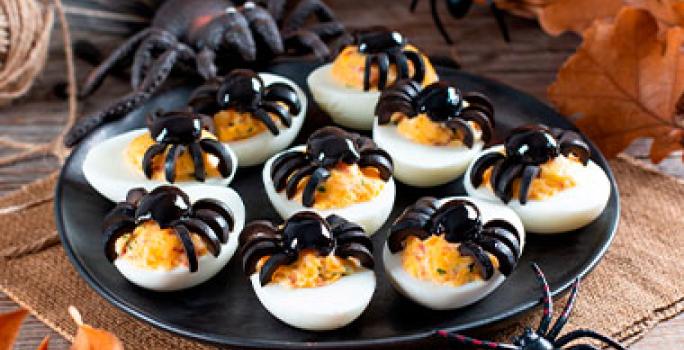 Huevos arácnidos sobre un plato negro para una fiesta de Halloween. Huevos arácnidos sobre un plato negro para una fiesta de Halloween.