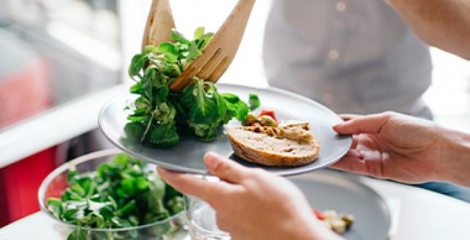 Las verduras y el pan son comidas vegetarianas muy útiles. Una persona sirve una comida vegetariana con verduras y pan.