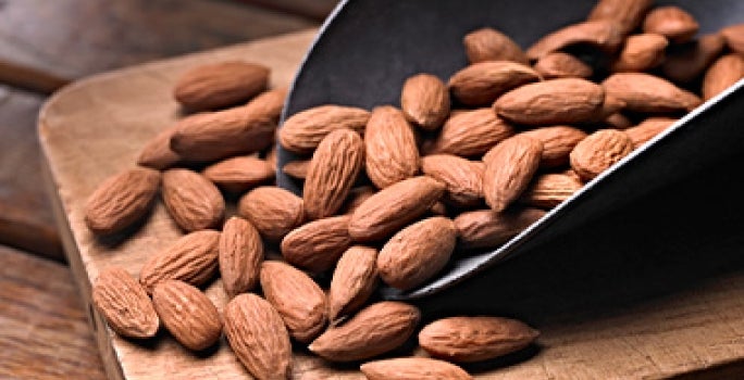 Cuchara y tabla con almendras enteras para pelar Cuchara y tabla con almendras enteras para pelar