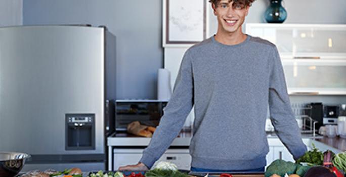 Hombre en cocina con diferentes alimentos, quitar mal olor del refrigerador Hombre en cocina con diferentes alimentos, quitar mal olor del refrigerador