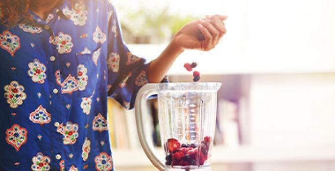 Mujer preparando acaí bowl añadiendo frutas en licuadora Mujer preparando acaí bowl añadiendo frutas en licuadora