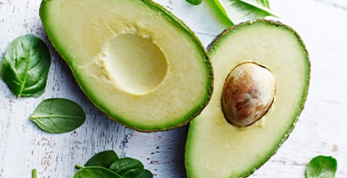 Palta partida por la mitad y hojas de espinaca alimentación balanceada Palta partida por la mitad y hojas de espinaca alimentación balanceada