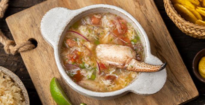 Plato de caldo de pescado con cangrejo, arroz y chips de plátano Plato de caldo de pescado con cangrejo, arroz y chips de plátano