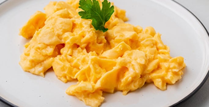 Los huevos revueltos son una forma muy común de hacerlos al desayuno. Huevos revueltos sobre un plato blanco.